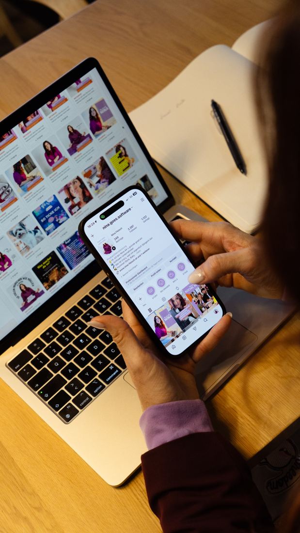 Nina Fleisch von hinten mit Handy und Laptop, auf beiden Bildschirmen die Social Suite